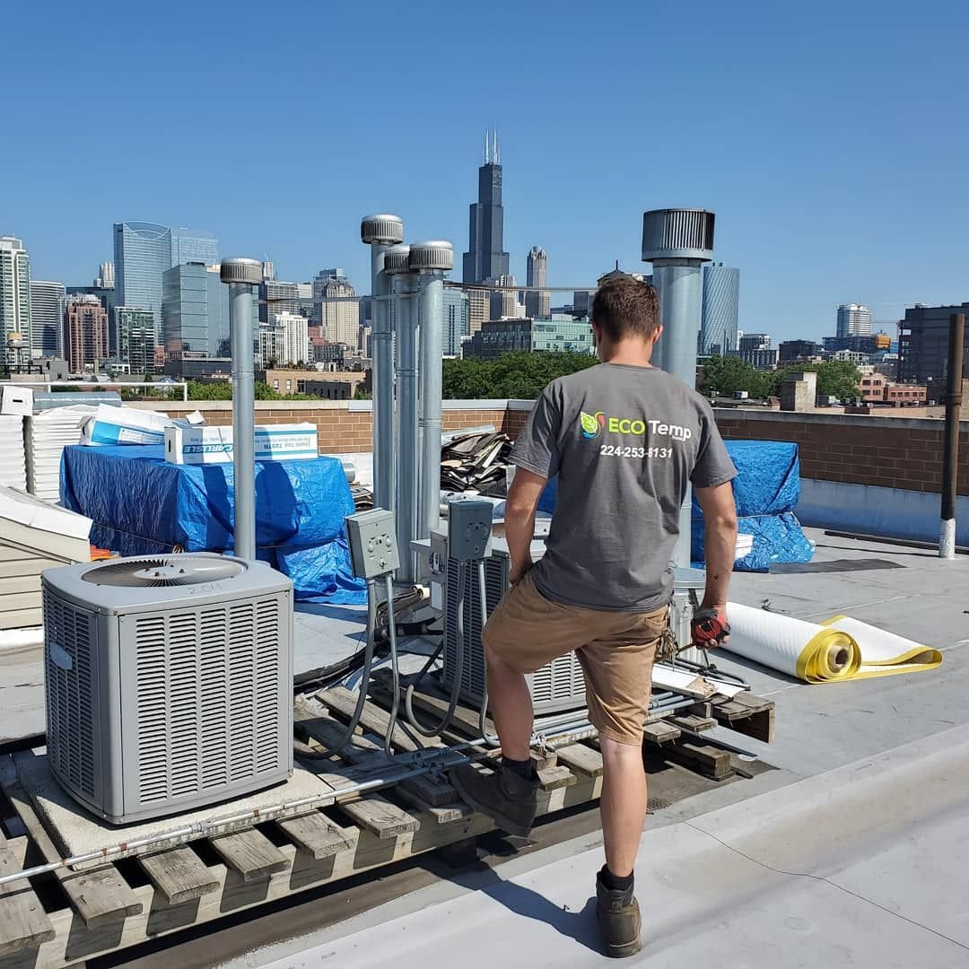 Jordan, owner of Eco Temp HVAC on a Chicago rooftop installing new air conditioning units for a commercial property.