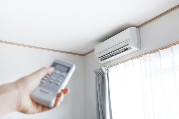 Hand with remote control directed at the ductless mini split air conditioner