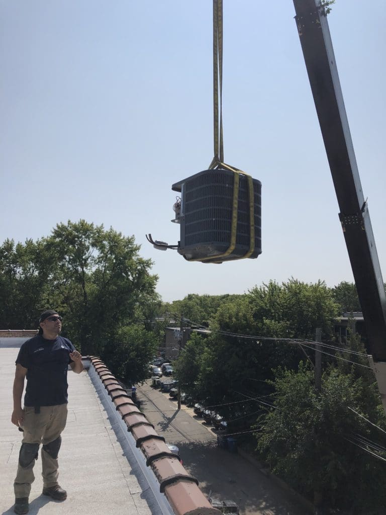 A crane hoisting an air conditioner onto a roof of a business in Palos Hills IL.