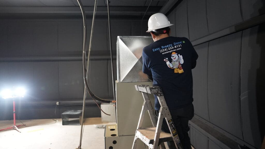 Technician working on a furnace plenum after replacing the old one.