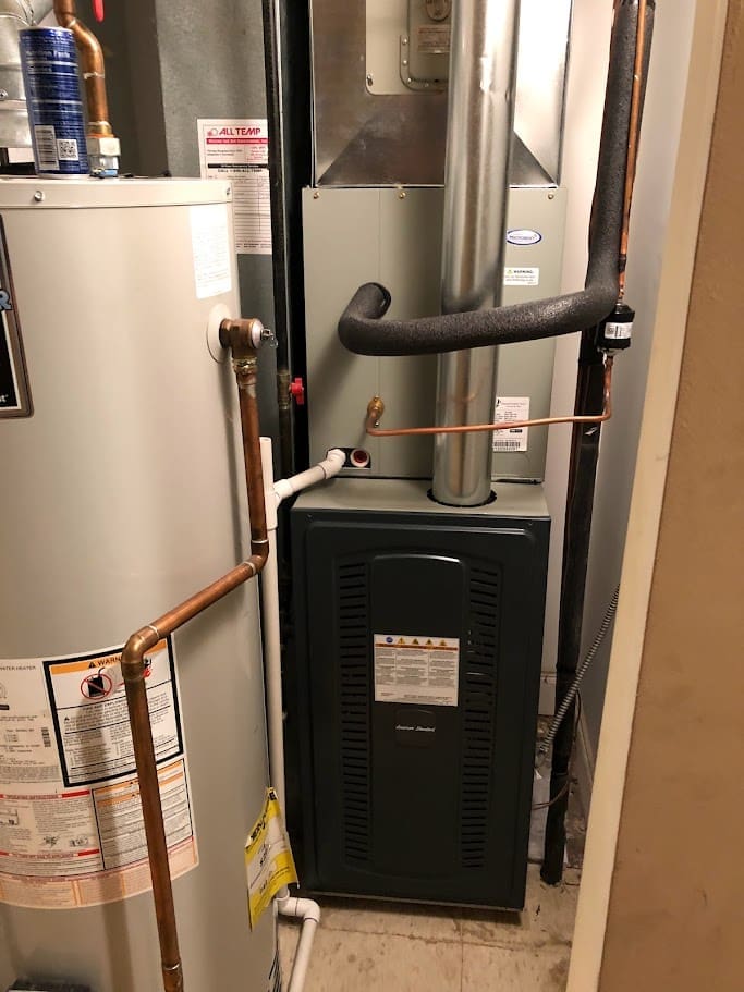 An American Standard Furnace and a tank water heater in a room.