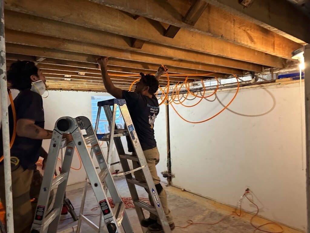 Two technicians installing HVAC lines in a Carpentersville home basement.