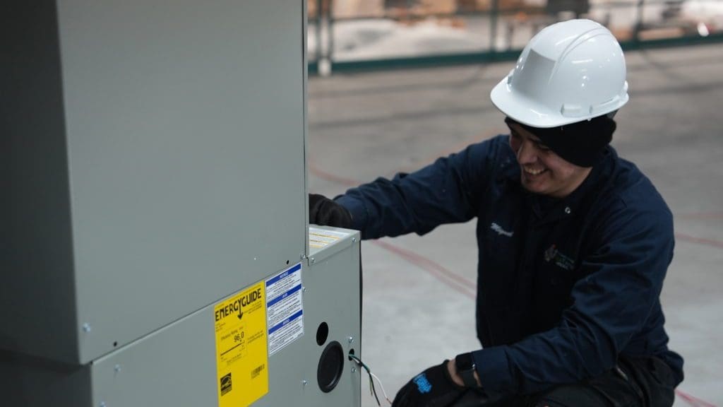 HVAC technician smiling while looking at furnace in Bloomingdale.