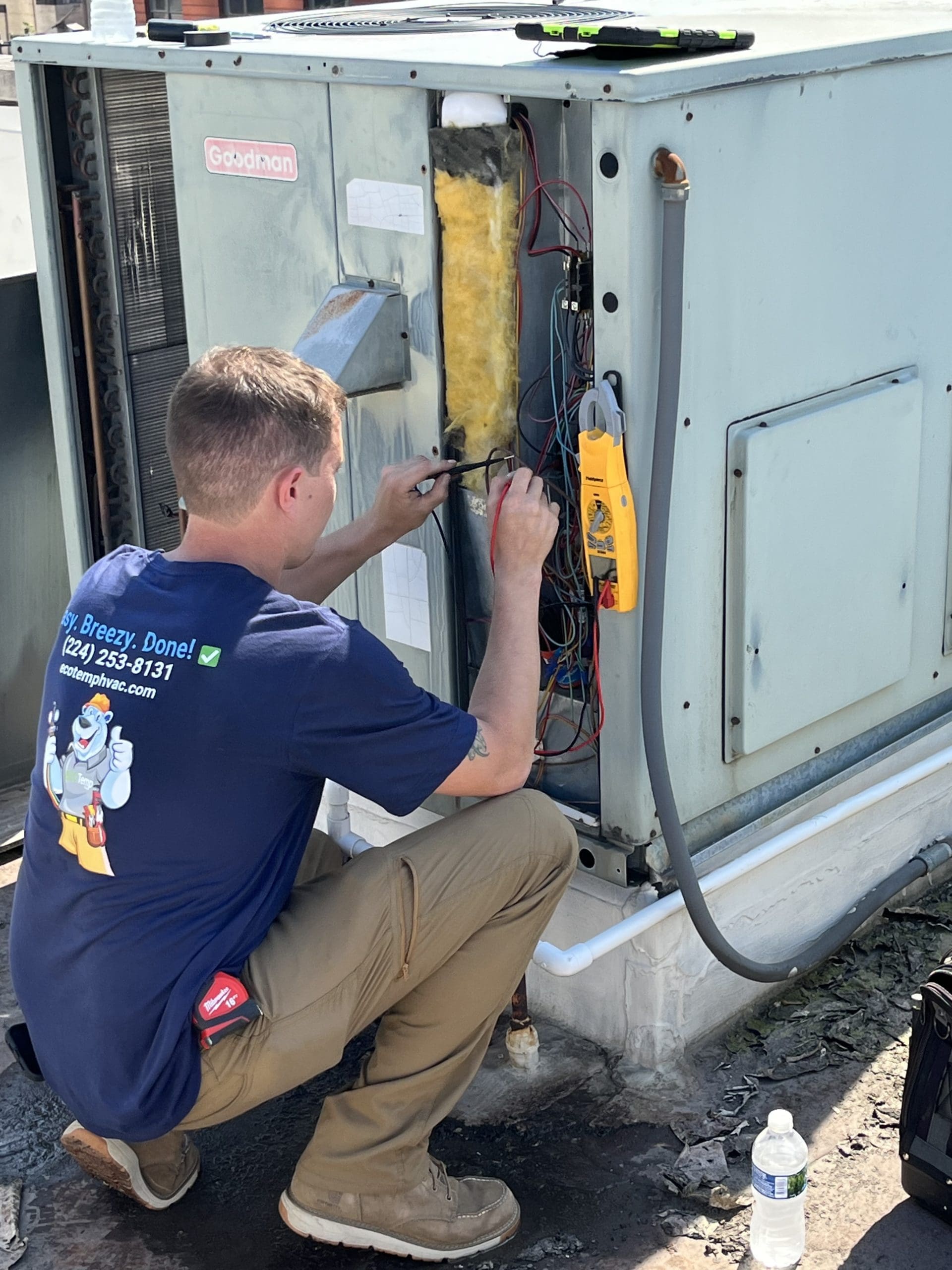 Technician using power wattage testing tools on a new outdoor RTU.
